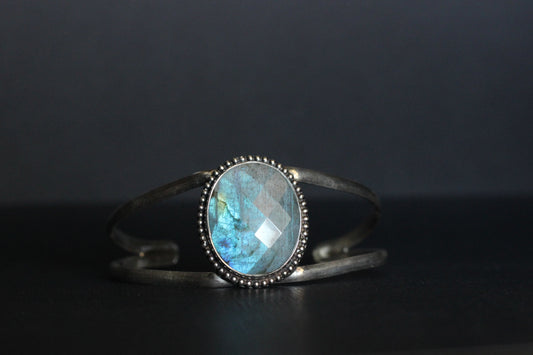 Silver bracelet with a blue labradorite gemstone on a dark surface